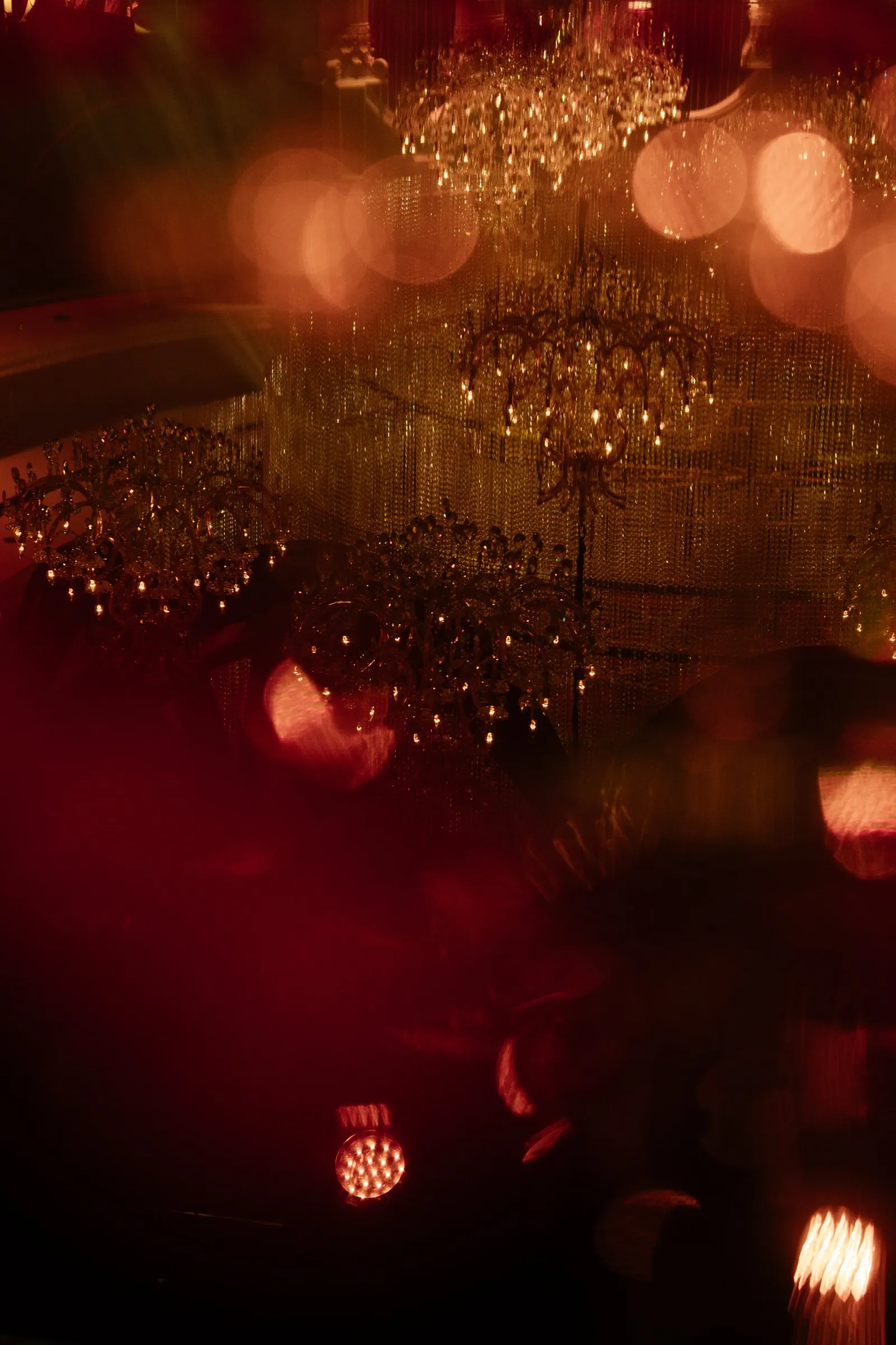 Crystal chandeliers glowing through soft red bokeh